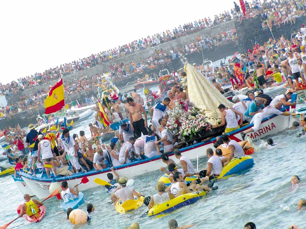 Piragüistas y bañistas  intentan tocar la imagen de la Virgen del Carmen y su barco