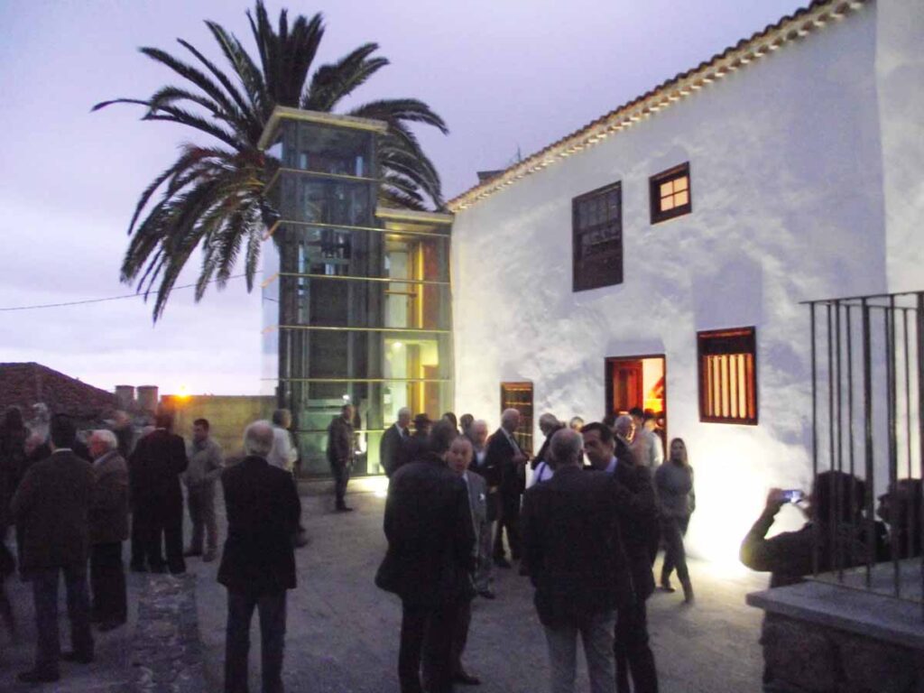 El ascensor de cristal junto a la gran palmera en el patio de La Casona