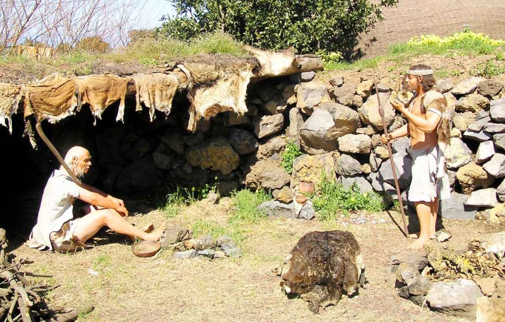 Dos guanches charlando delante de una cueva