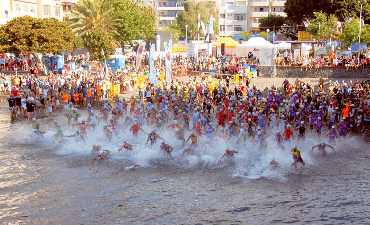 Tras el pistoletazo de salida los participantes del Triatlón de El Médano corren al agua para realizar la prueba de nado